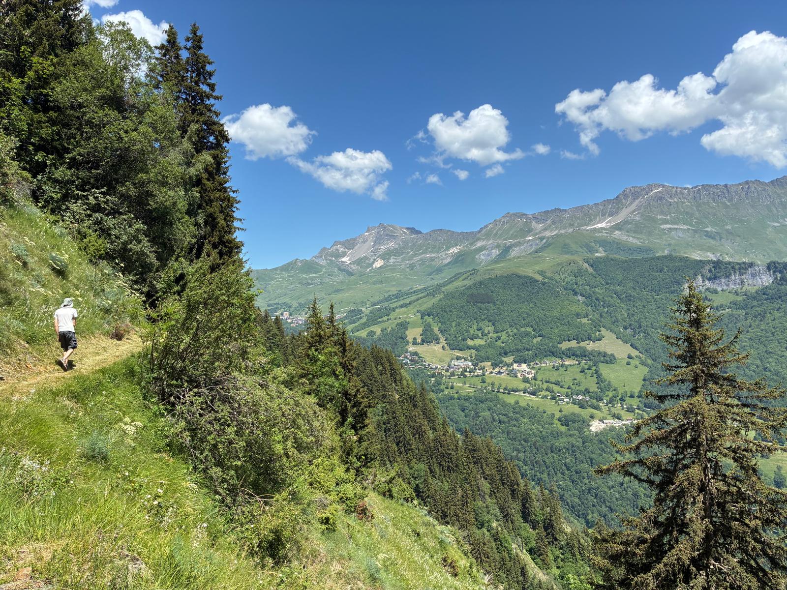 Randonneur sur un sentier d’été face à la vallée