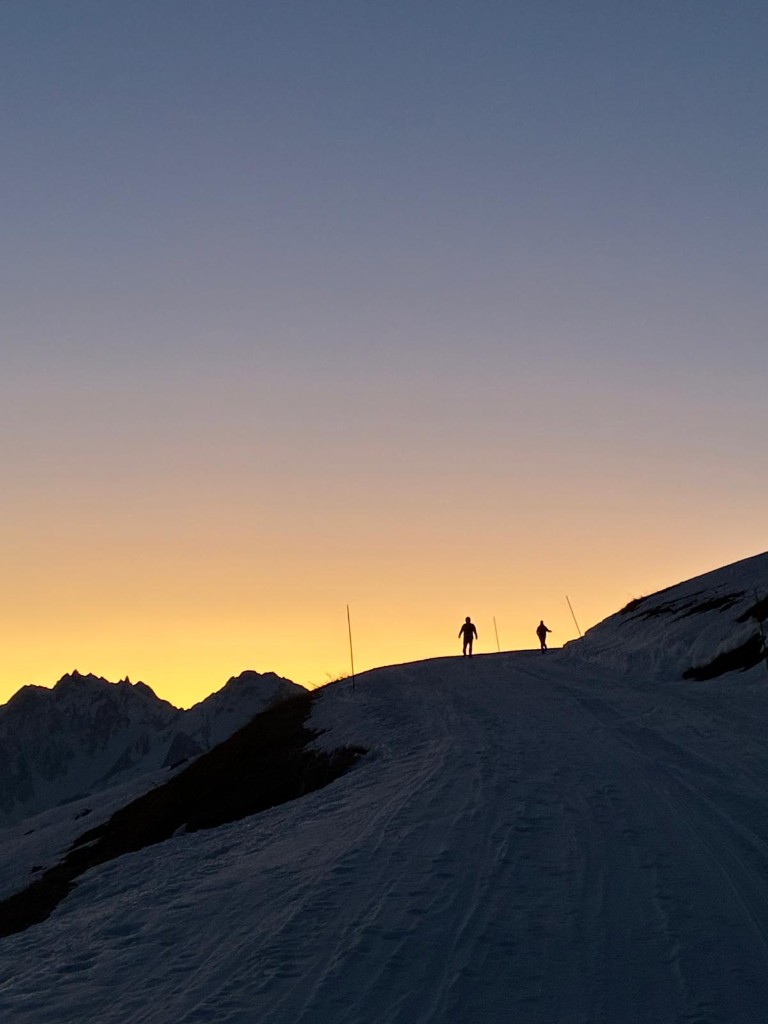 Deux skieurs en silhouette sur une crête au coucher du soleil